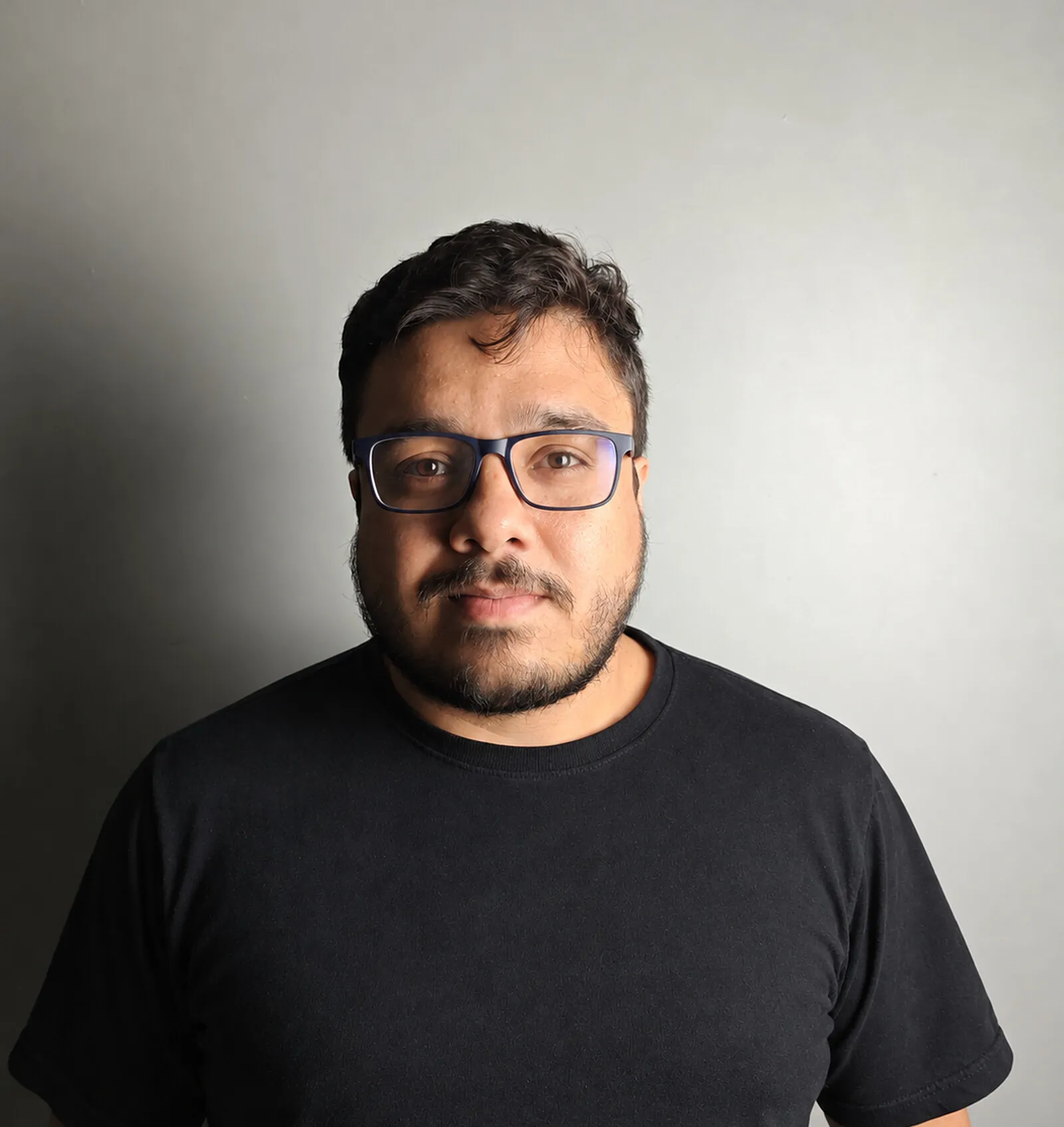 Retrato de Flavio Pereira dos Santos, de camiseta preta, sobre fundo cinza.